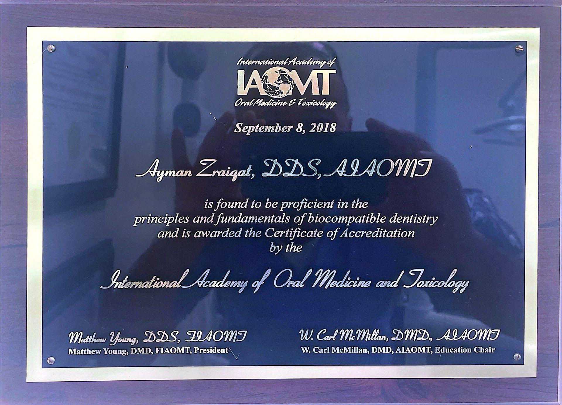A plaque certifying Ayman Zraigat, DDS, ALAOMT, for proficiency in biocompatible dentistry, awarded by the IAOMT.